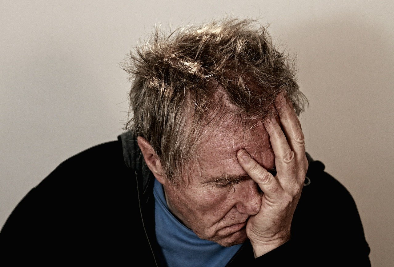 Image of man holding head courtesy of Pexels